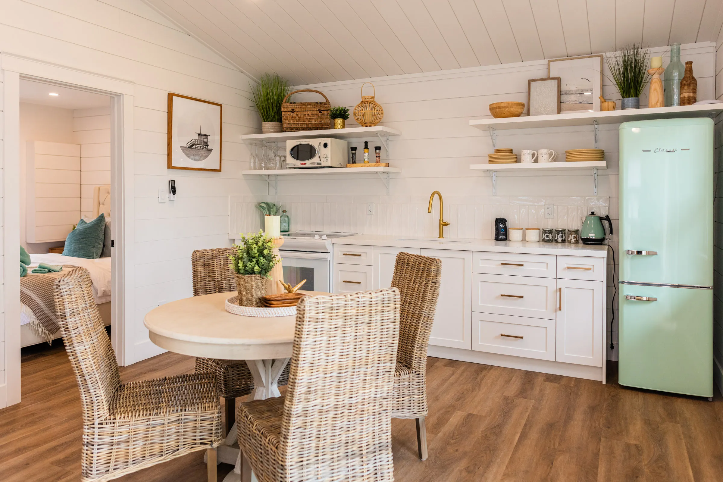 The Beach full kitchen, mint-green fridge and wicker dining chairs.