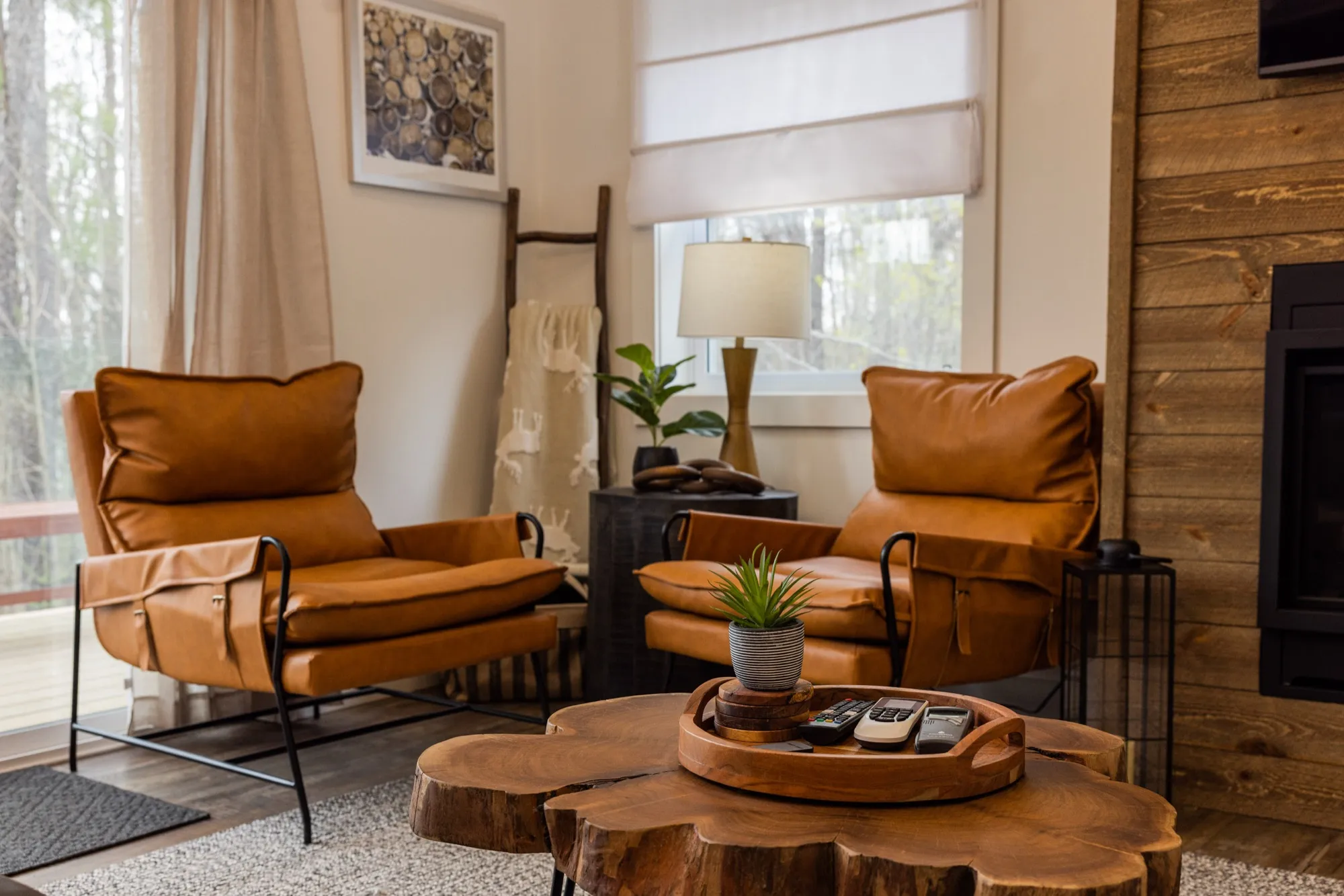 The Rustic Lodge living area, with two tan leather recliners beside a fireplace set into a wood-plank wall, and a live-edge stump table.