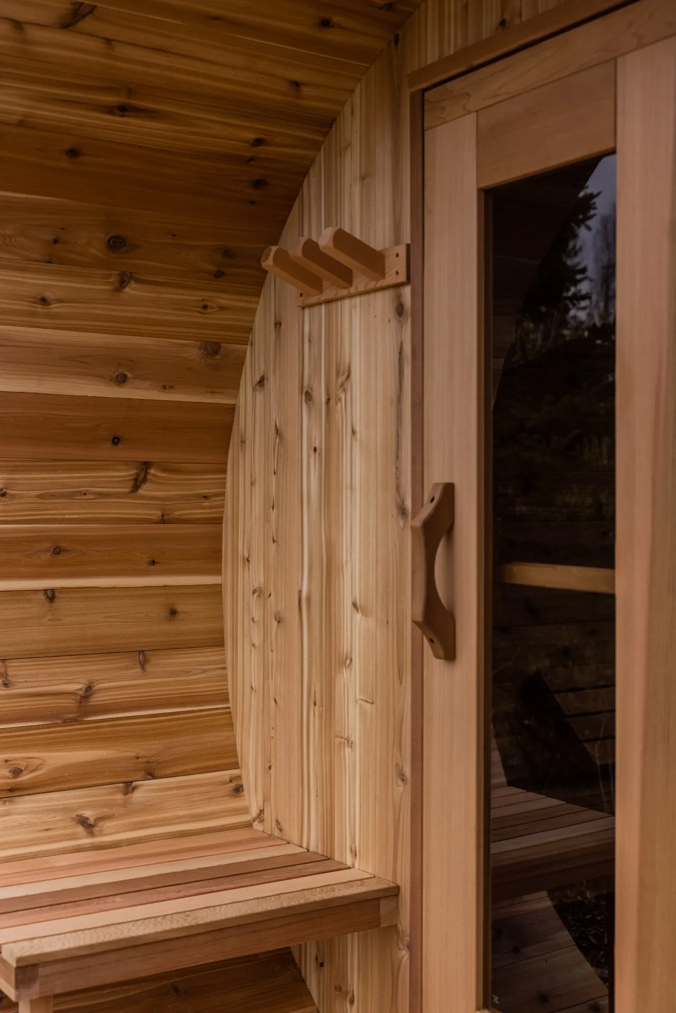 Inside the cedar barrel sauna, looking along the bench to the glass door.