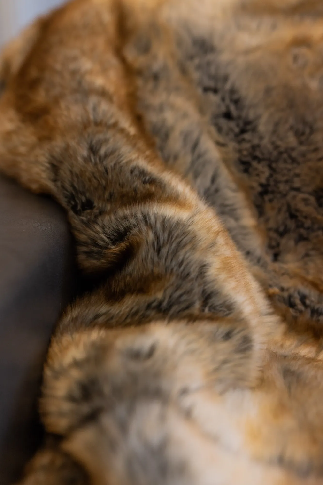 A soft faux-fur throw draped over the arm of a chair.