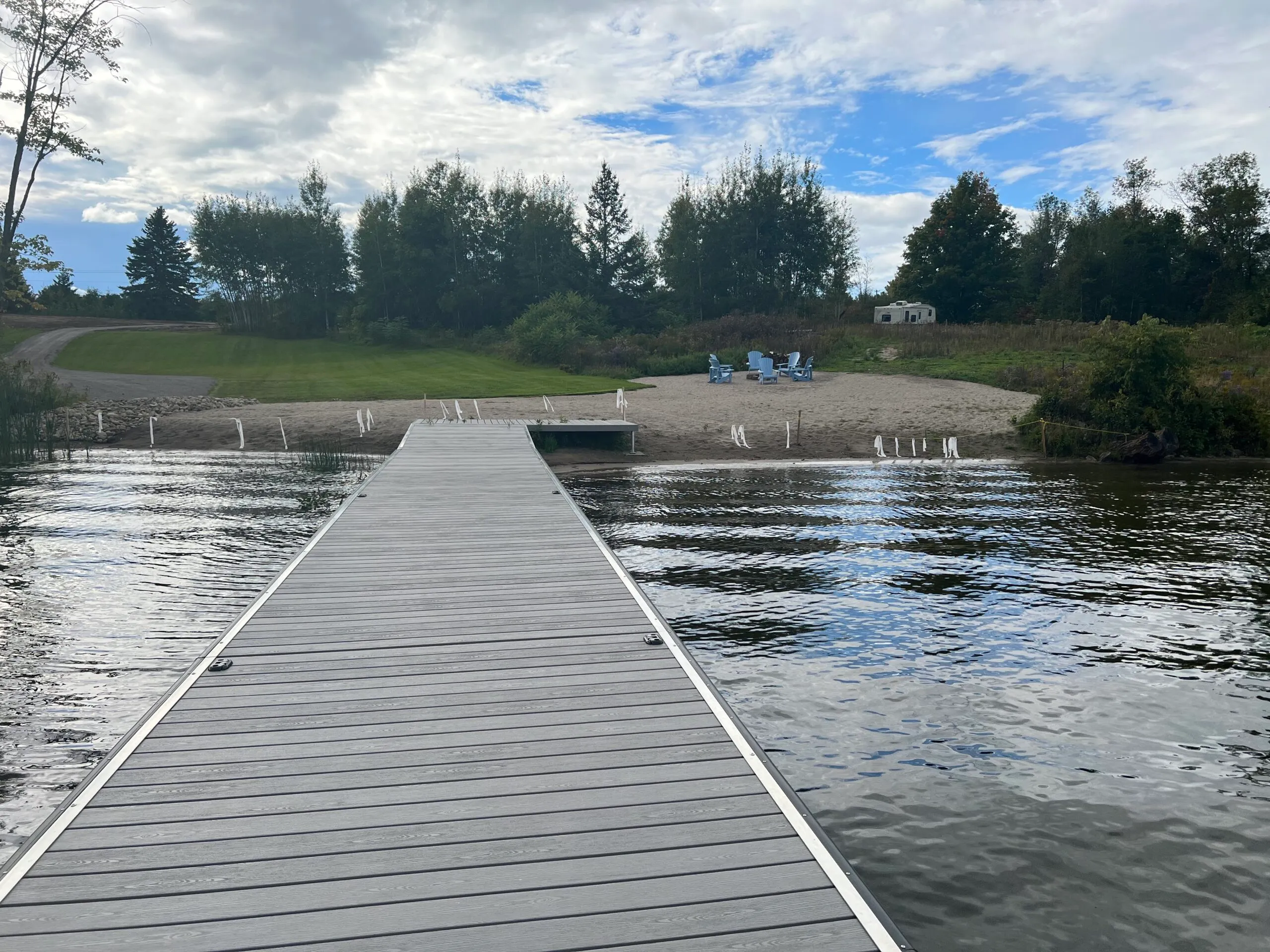 The resort dock leading back towards the beach and blue Adirondack chairs.